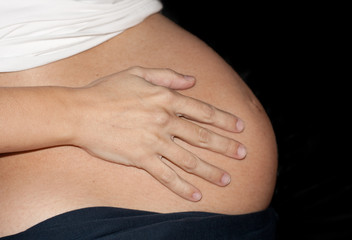 Embarazada de 9 meses de perfil con fondo negro, salida de cuentas, a punto de dar a a luz