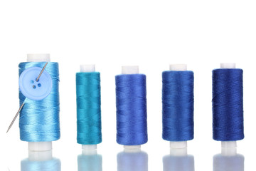 Many blue bobbin with needle and buttons isolated on white