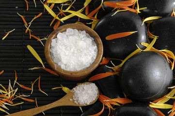 herbal salt in bowl with spoon and flower petals on pebbles