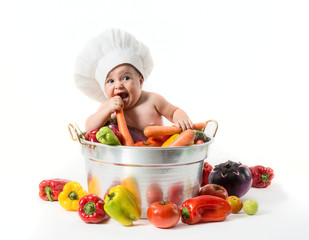 Bambino con cappello da cuoco dentro la pentola con ortaggi