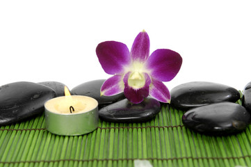 Fototapeta na wymiar Beautiful orchid kamieniami i świeca na zielonej maty słomy kij