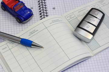 Büromaterial mit Fahrtenbuch und einem blauen Auto
