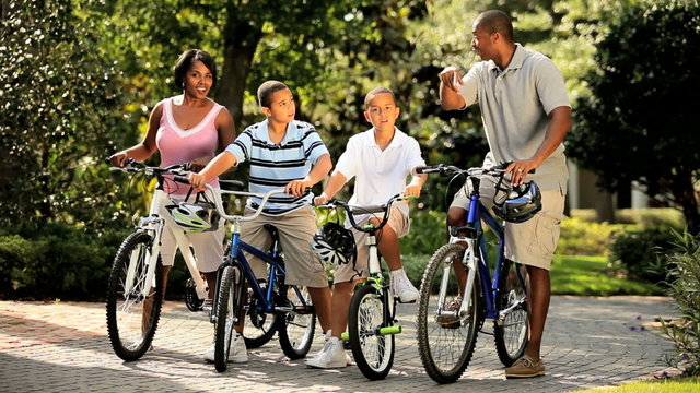 Ethnic parents cycling together with children