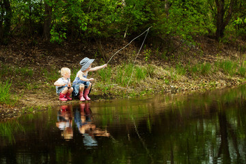 Little girls are fishing on lake in forest