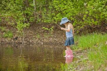 Little girl are fishing on lake in forest