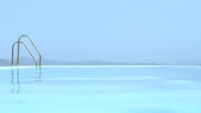 Man, walking on shallow steps in an infinity pool