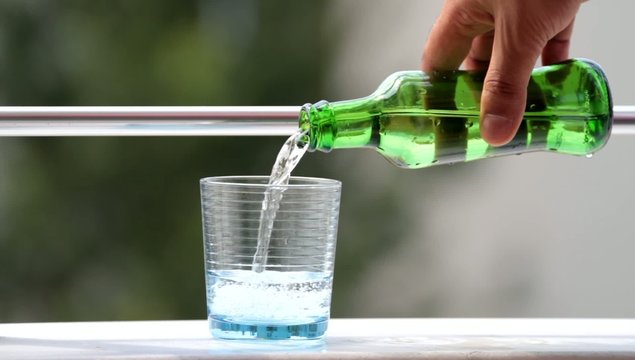 Cold mineral water pouring from  glass bottle into a  glass