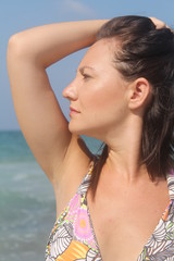 Beautiful brunette at the beach, holding her hair