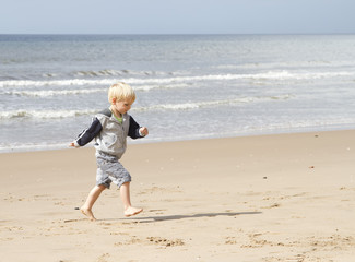 Blond young boy running on the beach