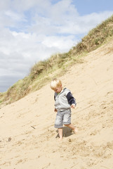 Young blond boy walking down sand dune