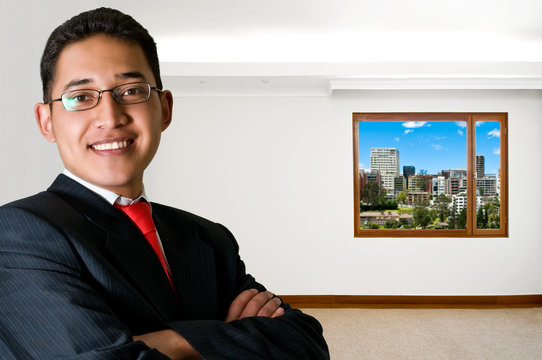 Isolated happy latin business man in empty office with cityscape