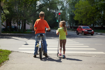 Boy with bicycle and his younger sister with scooter