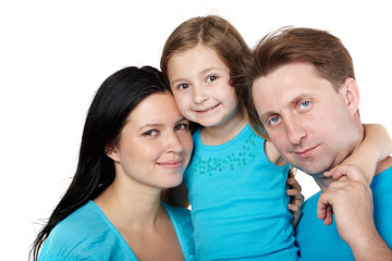 Family of three in blue shirts, little daughter hugs her parents