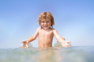 young happy child having fun in water on sky background