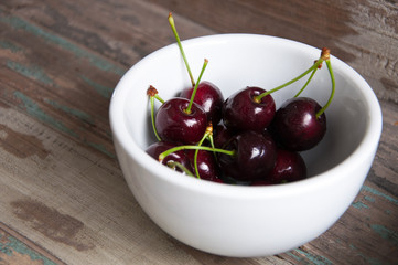 Fresh black cherries served in a white bowl on a breakfast tray.