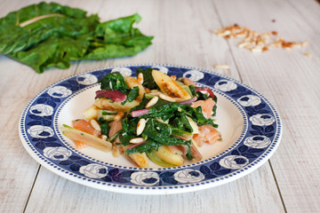 fresh salad with chard noodles and pine nuts on wooden table