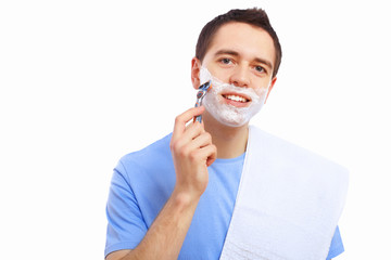 Young man at home shaving himself