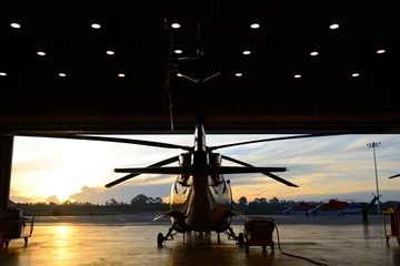 Poster Im Rahmen Silhouette des Hubschraubers im Hangar © num_skyman