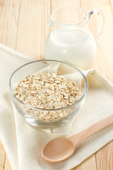 Oat flaks on a glass bowl and jug of milk