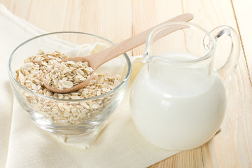 Oat flaks on a glass bowl and jug of milk