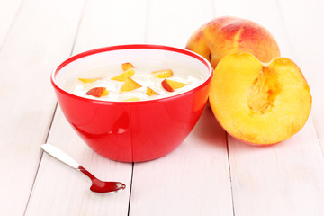 Yogurt with peach in bowl on wooden background
