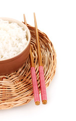 Bowl of rice and chopsticks on wicker mat isoalted on white