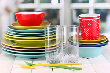 Colorful tableware on wooden table on window background