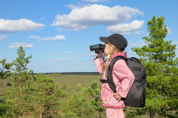 Little girl looking through binoculars from a high mountain