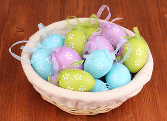 Colorful easter eggs in basket on wooden background