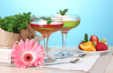 fruit jelly in glasses and fruits on table on blue background