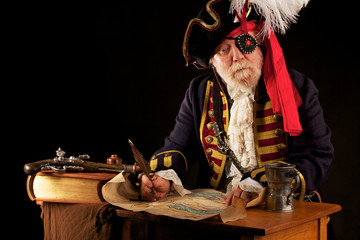 Old pirate captain drawing his treasure map using quill pen