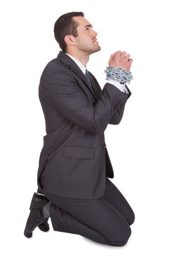 Businessman bound in chains begs for freedom