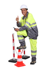 Man in high visibility overalls with a traffic cone and barrier