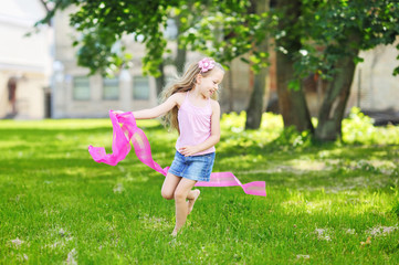 Sweet little girl runs with a ribbon in hand