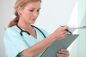 Blond female nurse holding clipboard