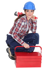 Portrait of a tradeswoman with a pipe wrench and a toolbox