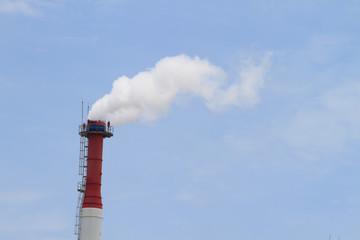 Plant pipe with smoke against blue sky