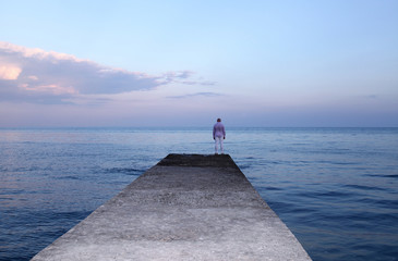Lonely man watching the sunset on the pier