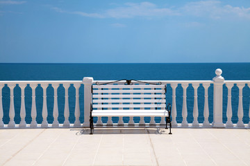 white bench, balustrade  and empty terrace overlooking the sea