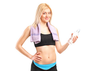 Attractive sportswoman with a bottle of water posing after train
