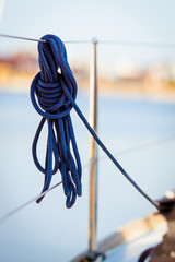 Blue rope. Tied blue rope hanging on a boat's railing
