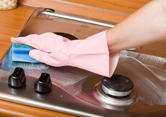 hand of the person in a rubber glove cleans a cooker