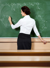 Teacher writes chemical formula at the blackboard