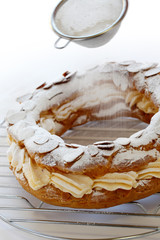 sifting powdered sugar over a paris brest.