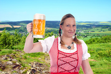 pretty woman in dirndl with beer mug in nature