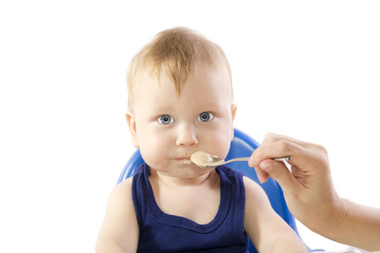 A young gray-eyed child feeding porridge
