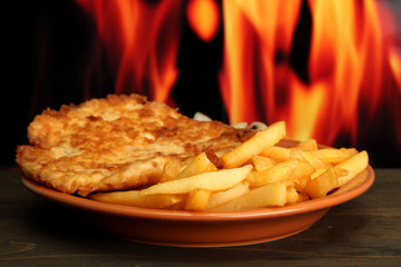 Roast chicken cutlet with french fries,  on fire background