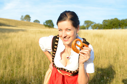 Lachende Frau im Dirndl mit Brezel
