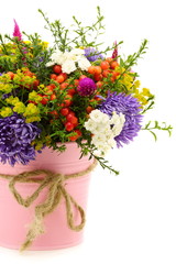 Bouquet of flowers and fruit in pink bucket.