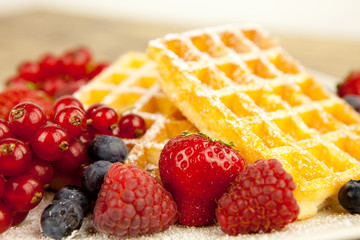 Frische Waffeln mit Puderzucker und Beeren auf einem Tisch